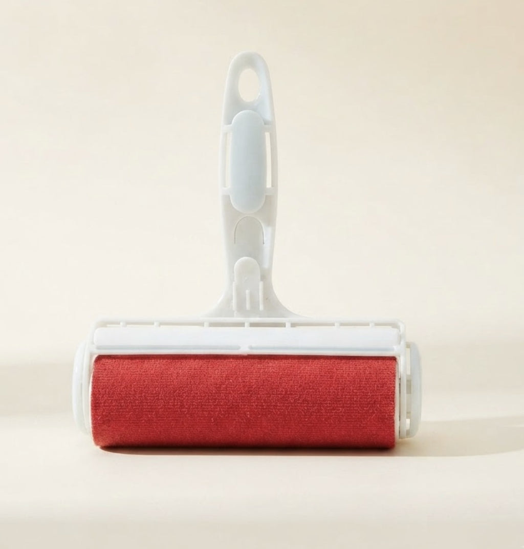 Rodillo quita pelos reutilizable para mascotas, cuerpo blanco con rodillo rojo, sobre fondo crema